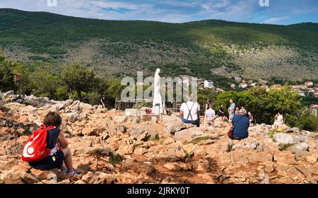 La statua della Beata Vergine Maria sul Podbrdo (collina delle apparizioni) e alcuni fedeli riuniti in preghiera (Medjugorje, Bosnia-Erzegovina) Foto Stock
