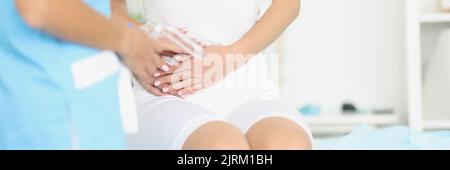 Ginecologo con strumento medico con specchio in piedi di fronte alla donna con adnexite Foto Stock