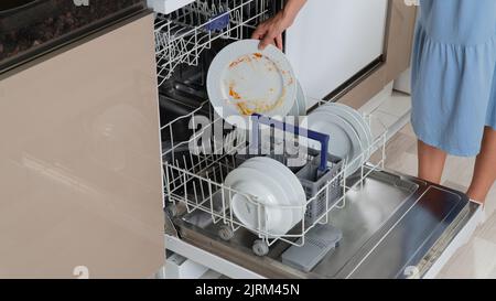 La mano di una donna mette un piatto sporco in lavastoviglie Foto Stock