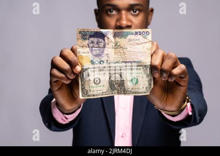 uomo nero che tiene le fatture del dollaro e della naira Foto Stock