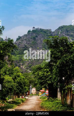 Un sentiero che porta a scale che si affacciano su Tam Coc da una pagoda in cima alle formazioni calcaree. La grotta MUA si trova in fondo. Foto Stock