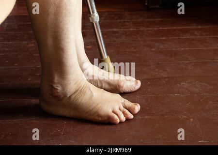 piedi di una vecchia nonna su un pavimento di legno sporco, solitudine, piedi di un vecchio uomo, un pensionato in povertà Foto Stock