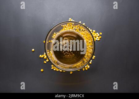 Bicchiere di birra su mais crudo, bicchiere di birra di mais su sfondo nero, idea di birra foto, foto isolata, foto vista dall'alto. Foto Stock