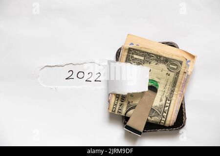 dollari in un portafoglio con una clip su uno sfondo bianco con il testo 2022, denaro in una clip per mantenere i soldi, la finanza nel nuovo anno 2022 Foto Stock