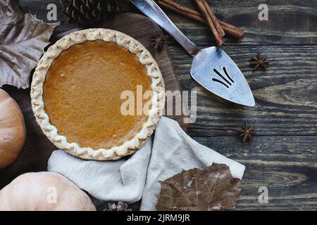 Una torta di zucca tutta fresca cotta su sfondo di legno con zucche mature, cannella e stella di anice. Vista dall'alto o piatta. Foto Stock