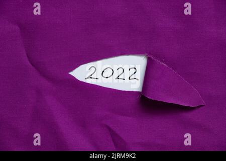 2022 scritto su carta su tessuto strappato, felice anno nuovo 2022, testo Foto Stock