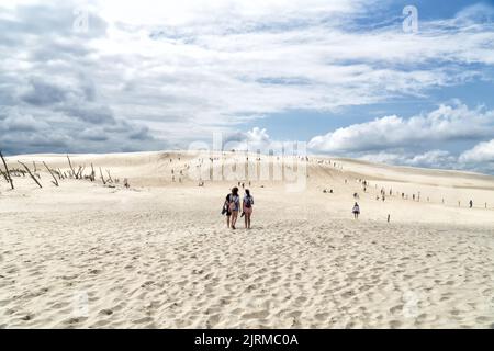 La gente esplora la duna di Lacka nel Parco Nazionale di Slowinski in Polonia. Duna in viaggio nella soleggiata giornata estiva. Spiaggia di sabbia e cielo blu con nuvole bianche. Foto Stock