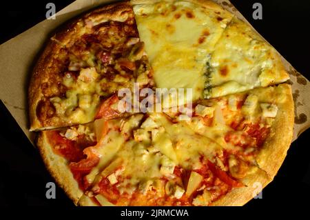 Tre tipi di pizza su sfondo scuro. Barbecue, pizza hawaiana e quattro formaggi. Foto Stock