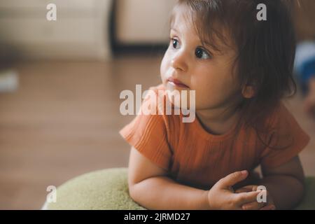 Bambina appoggiata sul divano e che guarda concentrata su ciò che verrà mostrato sul televisore. Relax nel fine settimana. Nuovo stile di vita dopo il covid Foto Stock