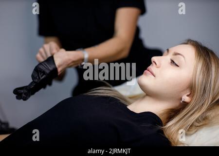 Il cosmetologo indossato i guanti prima di fare le labbra microblading procedura tatuaggio. Foto Stock