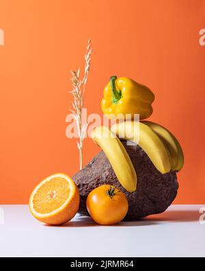 Set di deliziose arance succose, banane fresche e pepe giallo isolato su sfondo rosso. Nutrizione Foto Stock