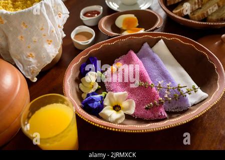 Tapioca. Colorate tapioca brasiliane servite in ciotole di argilla con fiori selvatici per la colazione. Foto Stock