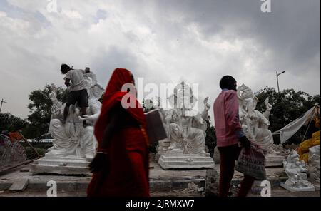 Nuova Delhi, India. 25th ago, 2022. La gente cammina davanti agli idoli della divinità indù a testa di elefante Ganesha davanti al festival di Ganesh Chaturthi a Nuova Delhi. Ganesh Chaturthi è un festival indù di dieci giorni celebrato per onorare il compleanno del Dio Ganesha, a capo di un elefante. Credit: SOPA Images Limited/Alamy Live News Foto Stock