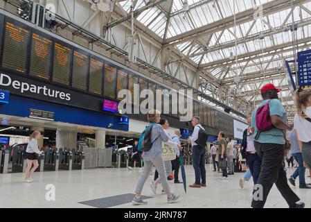 Vista dall'angolo basso dell'atrio della stazione della linea principale di Waterloo con i passeggeri in attesa che guardano il bordo di partenza, Londra, Inghilterra, Regno Unito Foto Stock