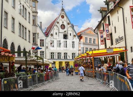 Una pittoresca strada acciottolata di caffè e negozi lungo il marciapiede vicino alla Casa del Vescovo nella città medievale vecchia di Tallinn, nella regione baltica del nord Foto Stock