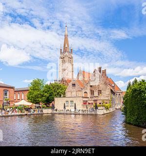 Guglia della Chiesa di nostra Signora (Onze-lieve-Vrouwekerk) che si affaccia sull'ospedale St Johns (Sint-Janshospitaal) e sulle vecchie case accanto al canale di Bruges. Foto Stock