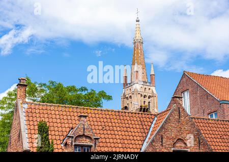 La guglia della Chiesa di nostra Signora (Onze-lieve-Vrouwekerk) che domina pantiled roves di vecchie case a Bruges, Belgio Foto Stock