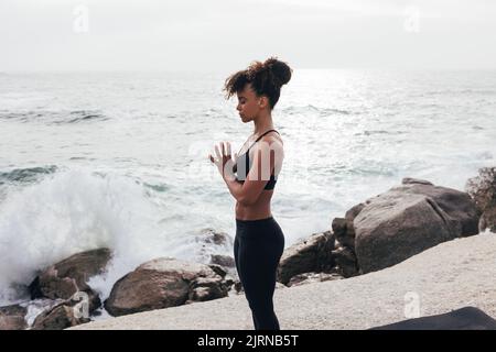 Vista laterale di una donna slim in abbigliamento sportivo a mani ripiegate con occhi chiusi Foto Stock