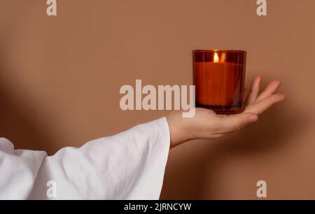 Coperto con una mano di panno bianco che tiene una candela sopra Foto Stock