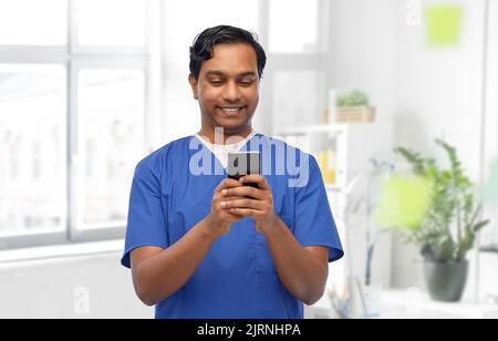 medico sorridente o infermiera maschile utilizzando lo smartphone Foto Stock