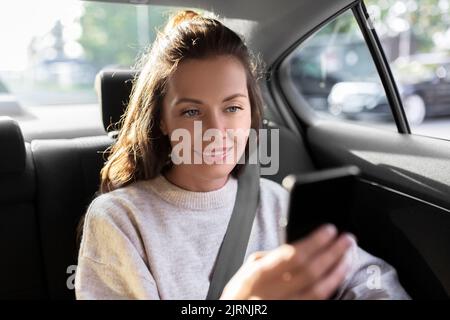 donna sorridente che usa lo smartphone in taxi Foto Stock