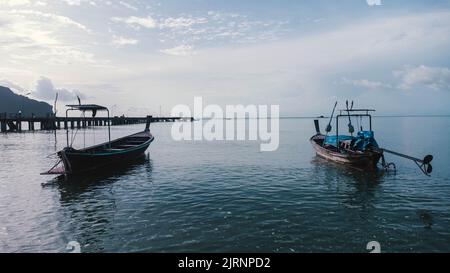 Bellissimo scenario di barche da pesca a riva con la bassa marea. Nel mare tropicale sono presenti molte barche tradizionali tailandesi da pesca a coda lunga. Molo del villaggio Foto Stock