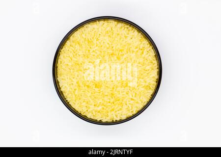 Un piatto di riso. Ciotola nera con grani di riso bianco su fondo bianco. Cibo sano. Riso bianco crudo macinato che ha avuto buccia, crusca, germe Foto Stock