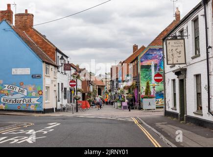 Negozi e murales dipinti sulle pareti degli edifici nel centro di Glastonbury, Northload Street Glastonbury, Somerset, Inghilterra, Regno Unito Foto Stock