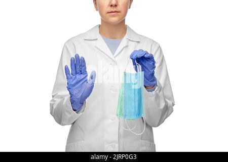 medico femminile con due maschere che mostrano il gesto di arresto Foto Stock