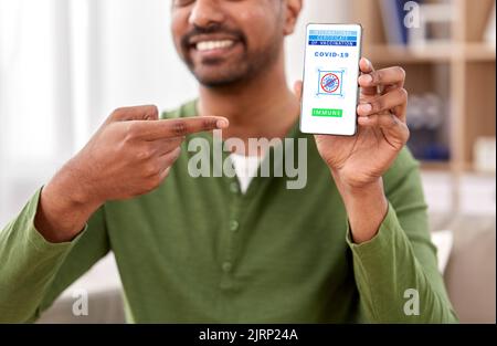uomo con certificato di vaccinazione su smartphone Foto Stock