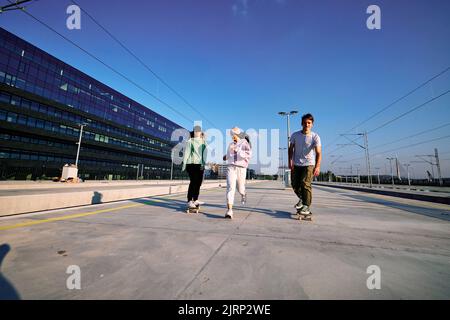 Tre giovani eccitati trascorrono del tempo nell'esterno urbano. Sono in corsa e skateboard. Foto Stock