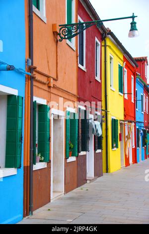 Primo piano della facciata di piccole case di vari colori luminosi. Sullo sfondo il cielo blu chiaro. Pittoresca immagine di strada con case colorate. Tipo Foto Stock