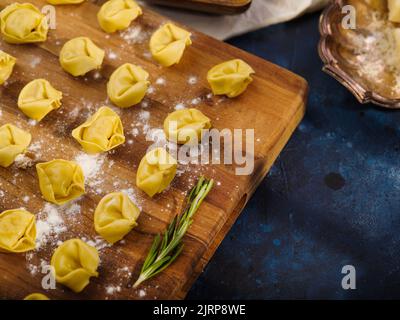 Appetitosi gnocchi, ravioli su un tagliere di legno su sfondo blu scuro. Processo di cottura. Vista ad angolo basso. Ristorante, hotel, caffetteria, cucina casalinga Foto Stock