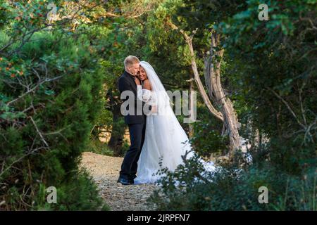 Sposi novelli interrazziali che abbraccia lo sfondo di un bellissimo paesaggio forestale Foto Stock