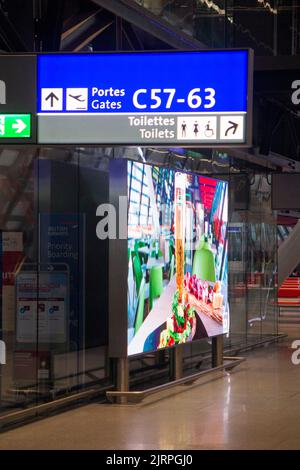 I cancelli di partenza firmano nell'atrio dell'aeroporto, e un grande schermo LCD pubblicitario che mostra annunci in continuo movimento, all'interno della nuova sala partenze/sala partenze/sale partenze modernizzate a Ginevra/aeroporto di Ginevra 'Cointrin' Svizzera. (131) Foto Stock