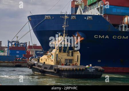 Odessa, Ucraina SIRCA 2019: Nave da carico ormeggio al porto con supporto per nave da rimorchiatore. Nave da rimorchiatore ravvicinata. Foto Stock