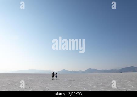 Giovane coppia che cammina via tenendo le mani su Bonneville Salt Flats Foto Stock