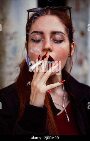 Primo piano di una ragazza dai capelli rossi che fuma un'articolazione Foto Stock