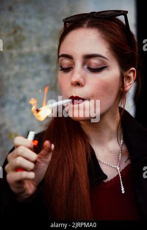 Primo piano di una ragazza dai capelli rossi che fuma un'articolazione Foto Stock
