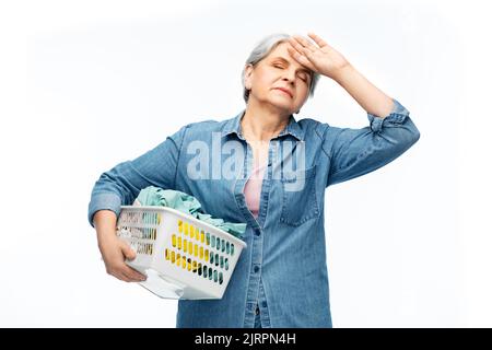 donna anziana stanca con cesto per la lavanderia Foto Stock