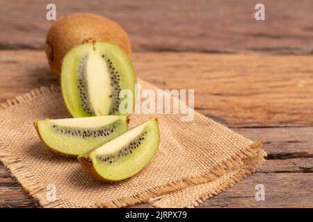 fettine di kiwi freschi sul sacco marrone posto sul vecchio tavolo di legno Foto Stock