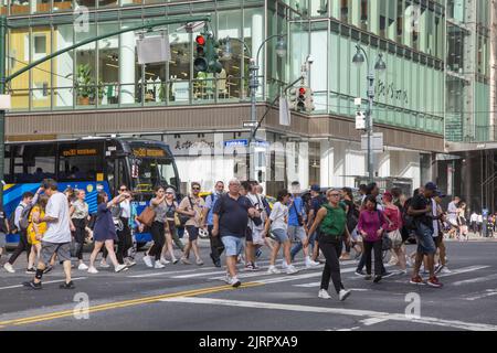 42nd Street a 5th Avenue è sempre affollata con pedoni sul marciapiede e strada e traffico Foto Stock