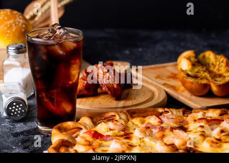 Pizza servita con bevanda fredda sul tavolo nero Foto Stock