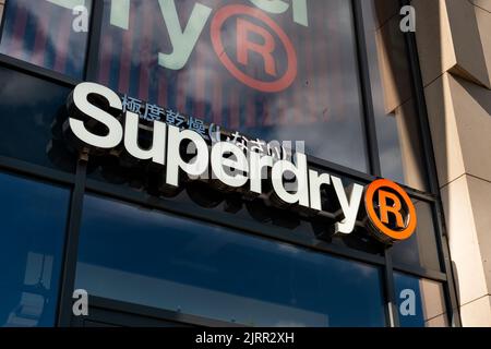 Logo Superdry fashion label sulla facciata di un negozio. L'esterno dell'edificio dei negozi nel centro della città. Grande cartello sopra l'entrata quando si acquista per l'abbigliamento. Foto Stock