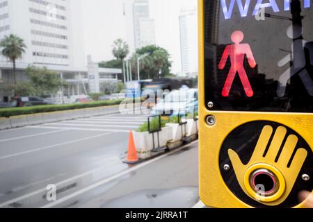 Il segnale di attesa si trova nell'area pedonale di attraversamento pedonale su una strada trafficata della città Foto Stock