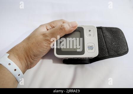 Tensiometro digitale con la mano del paziente sul letto d'ospedale Foto Stock