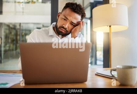 Stress, burnout e occhi tristi di un uomo d'affari sul notebook che lavora tardi su un'e-mail a casa o a casa. Mal di testa, salute mentale e lavoratore deluso Foto Stock