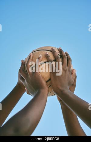 Lavoro di squadra, supporto e mani che tengono un basket all'inizio di una partita di campionato o di una competizione contro un cielo blu. Primo piano dell'afroamericano Foto Stock