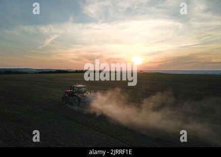 Trattore che irrorano fertilizzanti con prodotti chimici insetticidi erbicidi su campo agricolo al tramonto Foto Stock