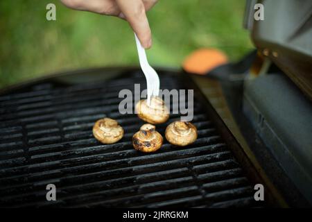 I funghi vengono grigliati. Dettagli picnic. Cibo su grata di acciaio. Cucina in estate. Foto Stock